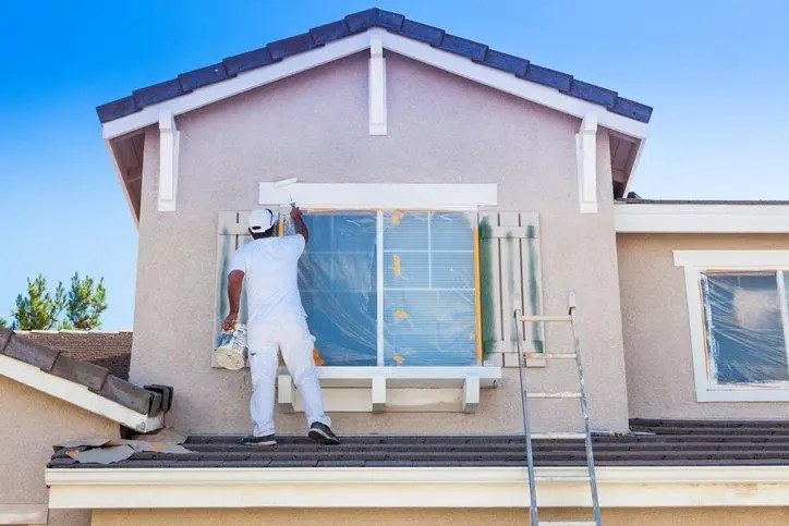 person paiting exterior of house